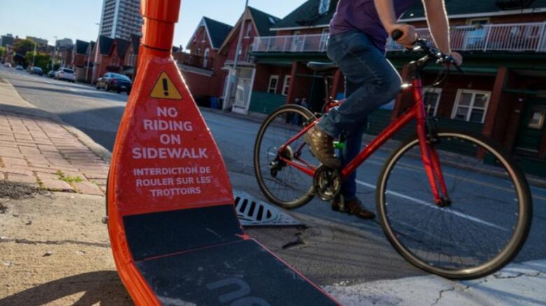 A close up of an e-scooter says no riding on sidewalk.