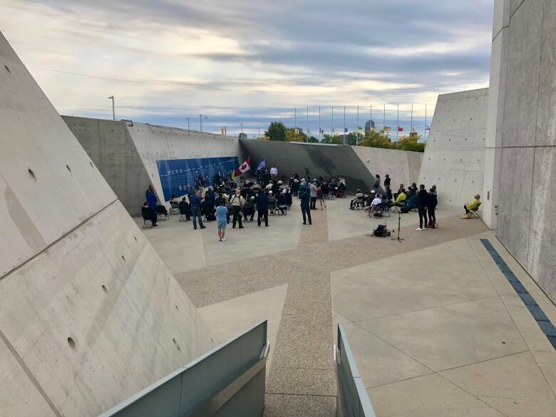 A few dozen people gather inside a concrete monument.