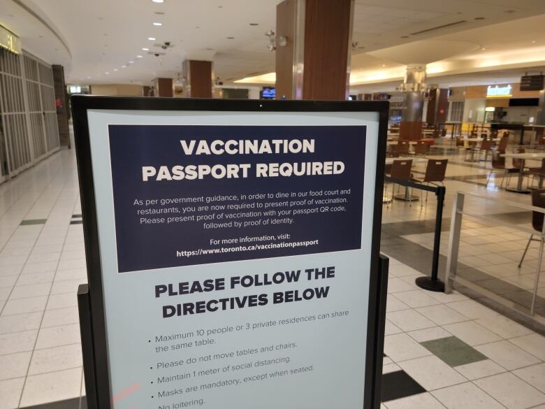 A sign in front of a food court regarding vaccine passports.