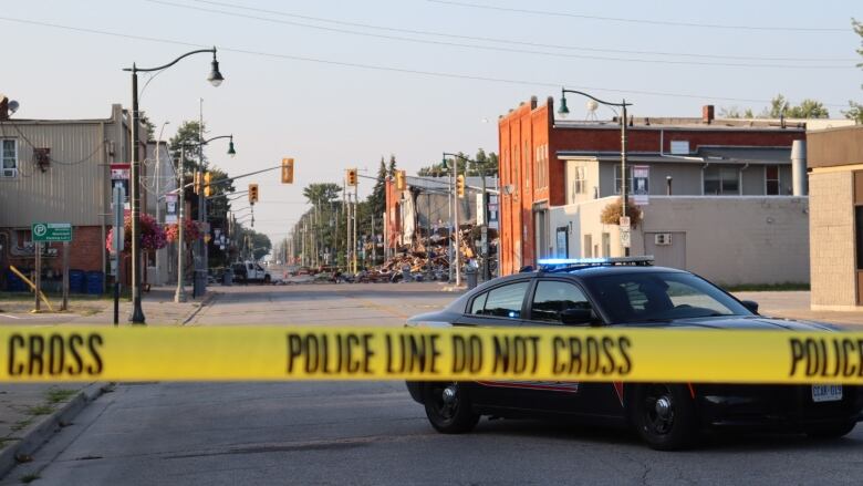 A street with police tape and damaged buildings in the background