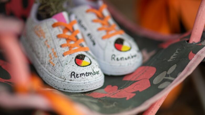 A child's pair of shoes with orange laces and the word 