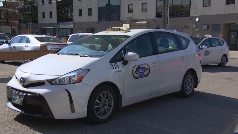 A white vehicle with a yellow taxi sign on top