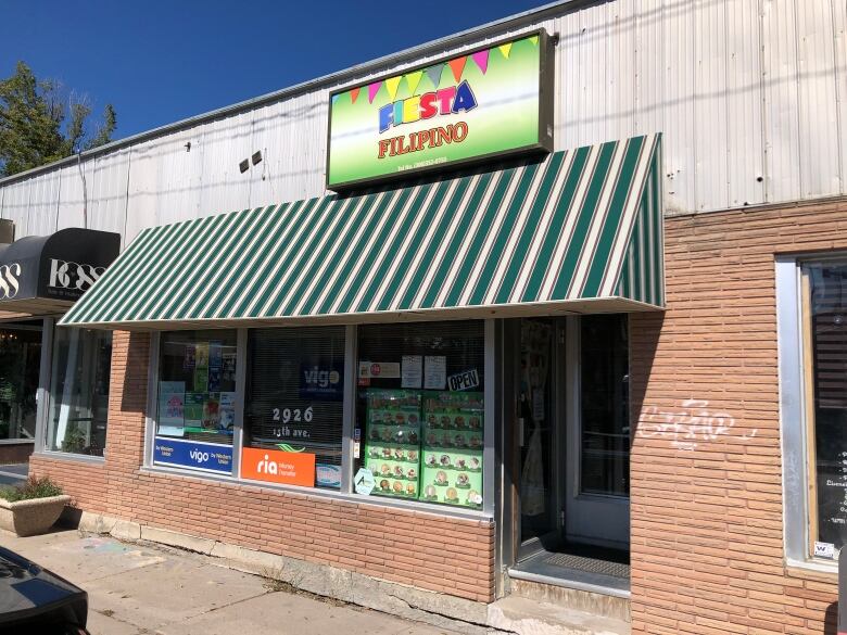 A low-rise brick building with a green and white awning and multi-coloured sign.