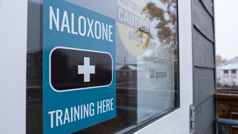 A sign on a glass door reads, 'Naloxone training here.'