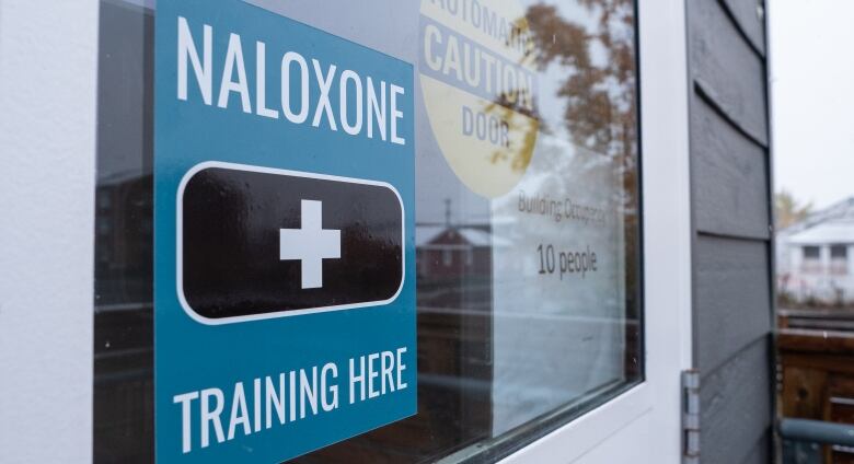 A sign on a glass door reads, 'Naloxone training here.'