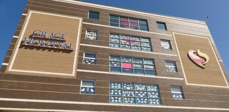 The exterior of a brown building is seen against the backdrop of a blue sky. The building is Grace Hospital.