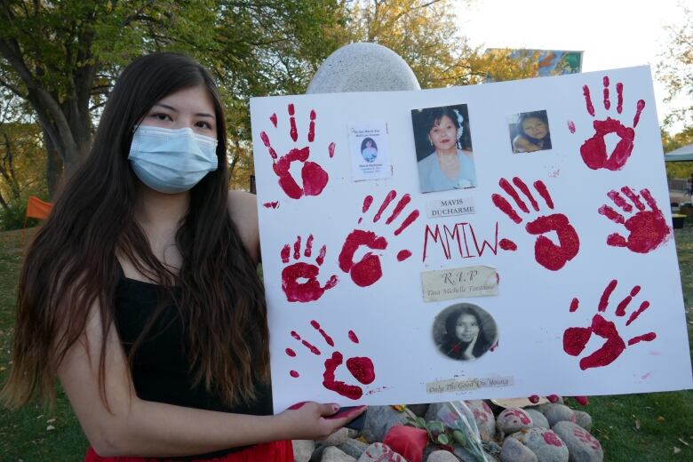 A woman holds up a MMIWG poster in honour of their aunt who died.