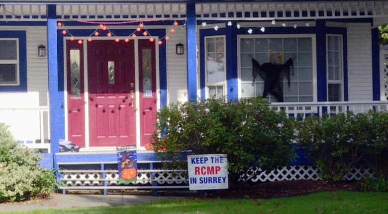 Keep the RCMP in Surrey sign next to a house.