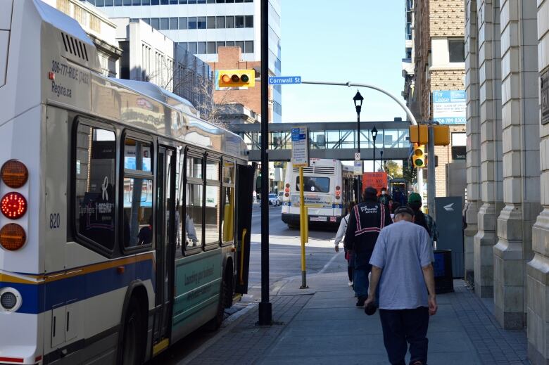 A group of people walk beside a Regina Transit bus on 11th Avenue in Regina, Sask. 