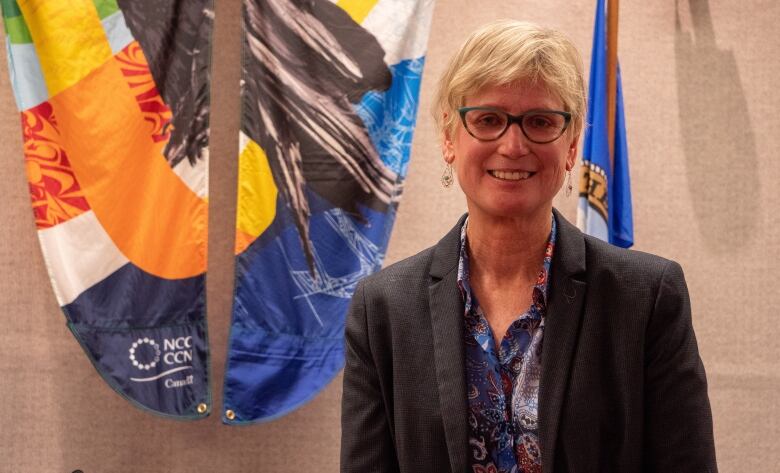 A smiling white woman in city council chambers.