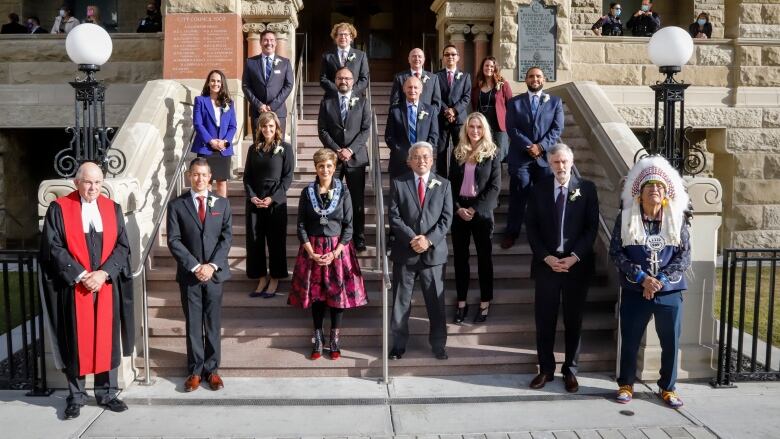 a group of people stand on a staircase outdoors and smile for a photo.