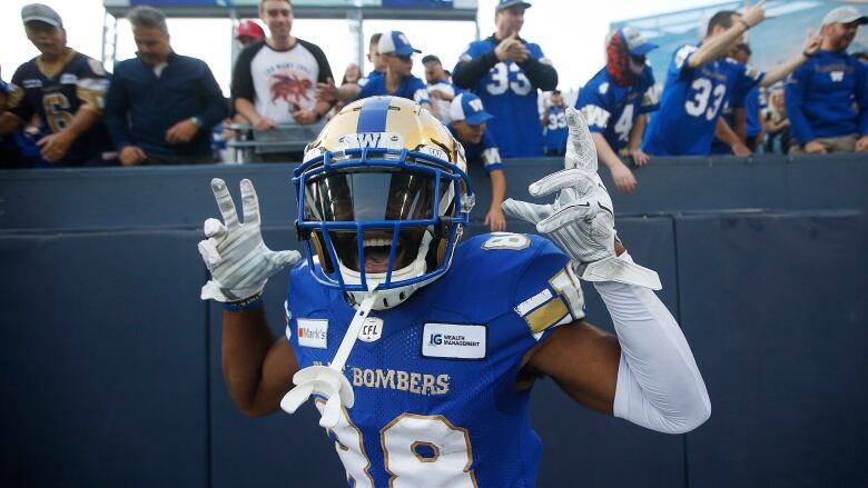 Football player smiles and raises his hands in celebration.