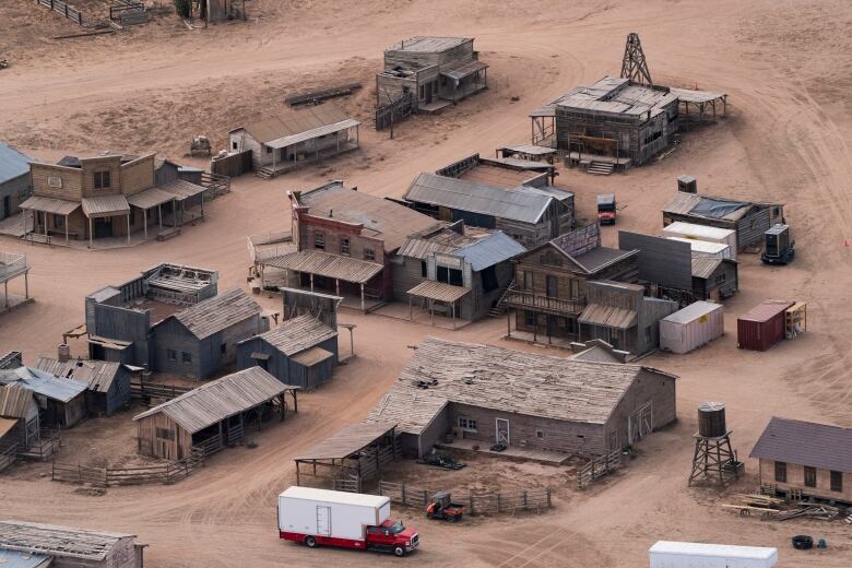 An aerial view of a Western movie set with several wooden buildings in the desert. 