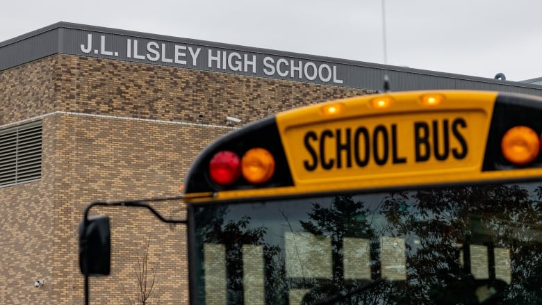 A sign for a high school and a school bus are shown.