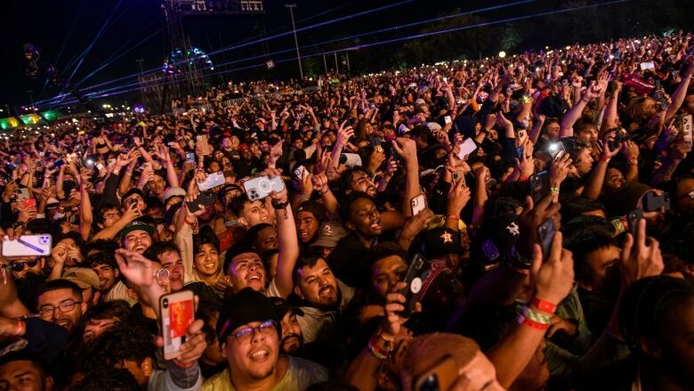 A crowd of people at an outdoor concert at night. 