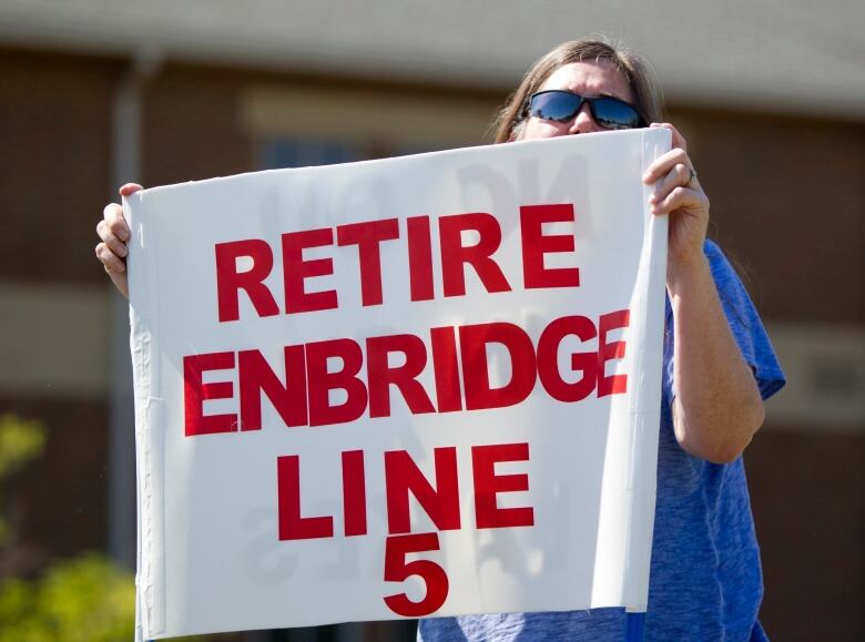 A woman holds a protest sign that says 