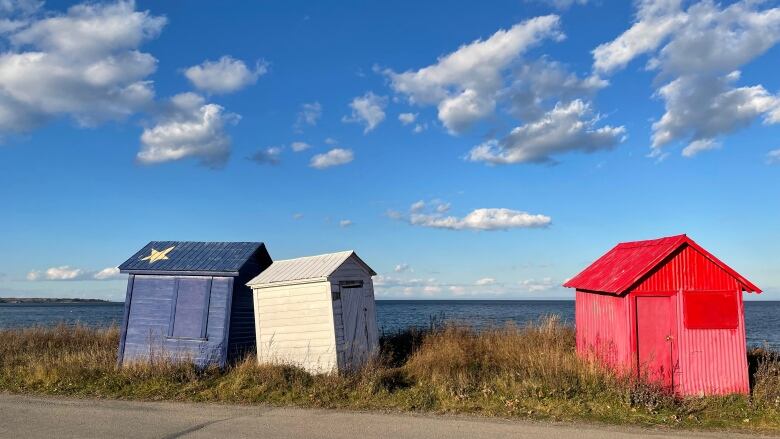 Three small huts painted in colours of Acadian flag