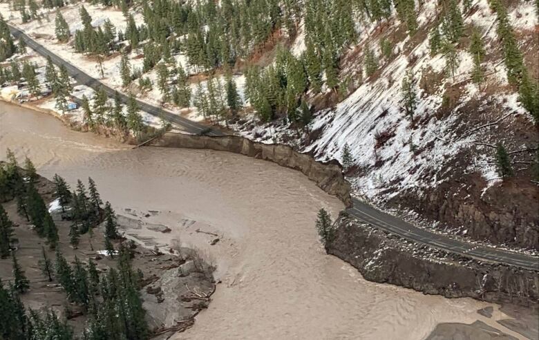 An aerial shot of muddy brown water encroaching on a roadway.