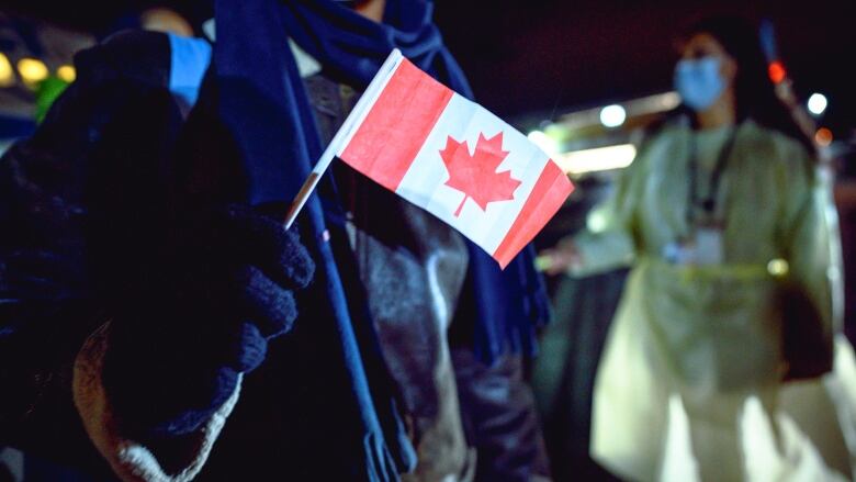 An Afghan refugee holds a small Canadian flag at the St. John's International Airport, on Oct. 26, 2021.  The Afghans at the centre of the lawsuit say they  have been waiting longer. 