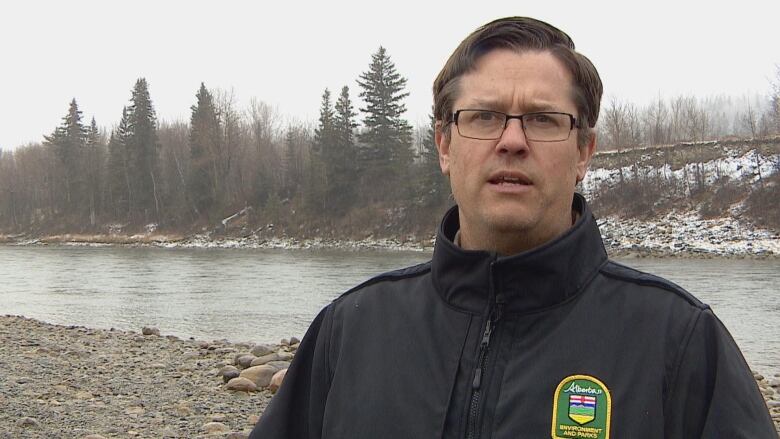 A man is pictured by a lake wearing a jacket.