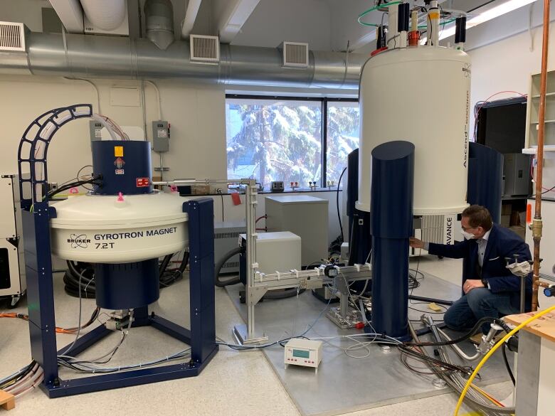 A man leans over an instrument using a superconducting magnet at the University of Alberta.