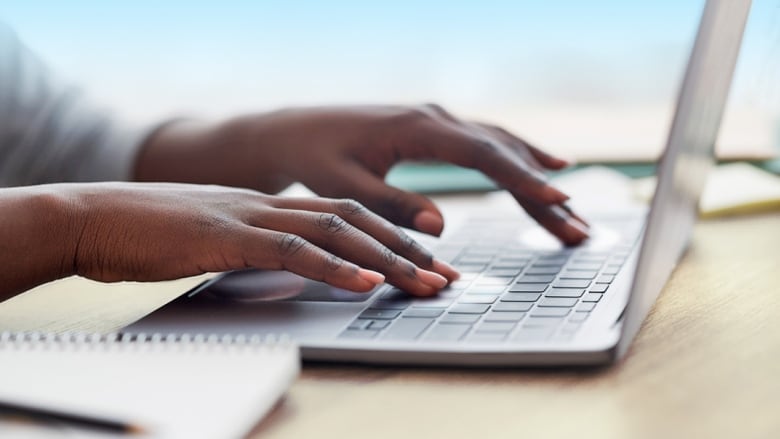 A close-up of hands typing on a laptop keyboard.