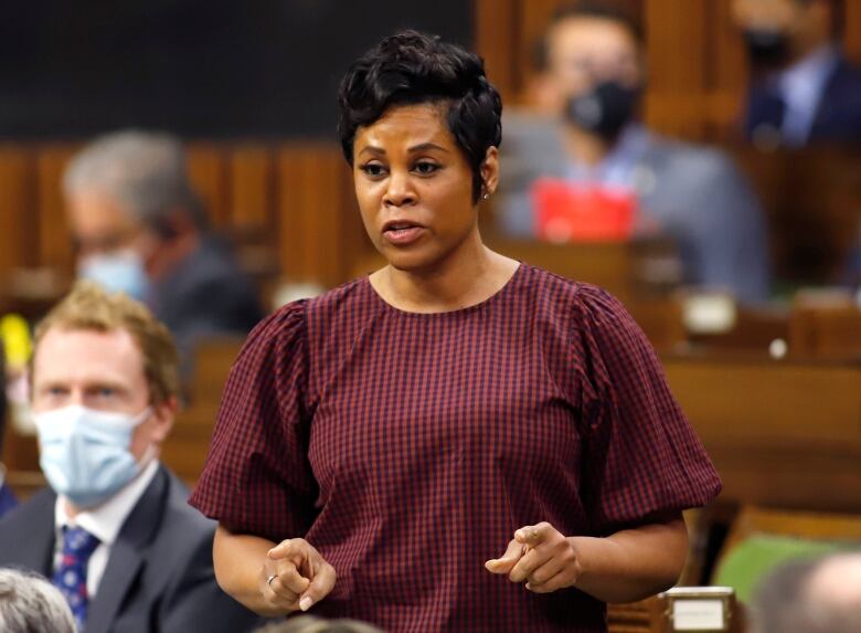 A woman in a red spotted blouse rises in the House of Commons.