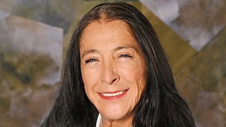 A woman with long black hair smiles into the camera.