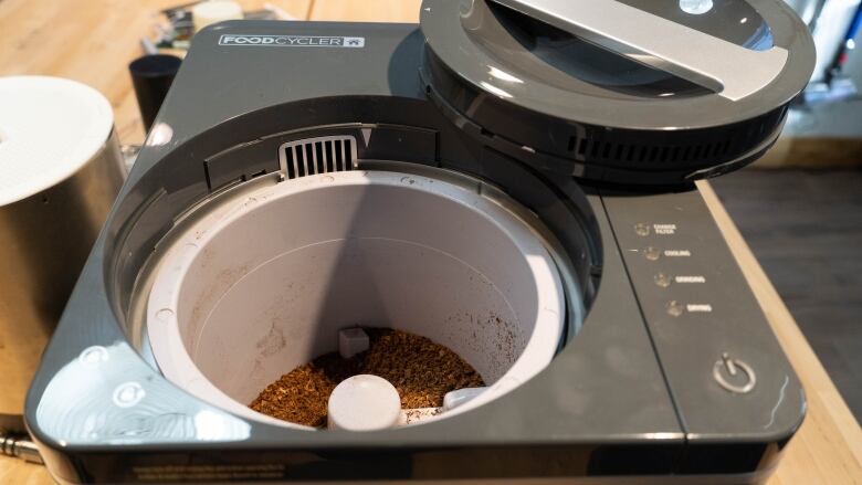 A circular opening in a box-shaped device, filled with a dirt-like material. 