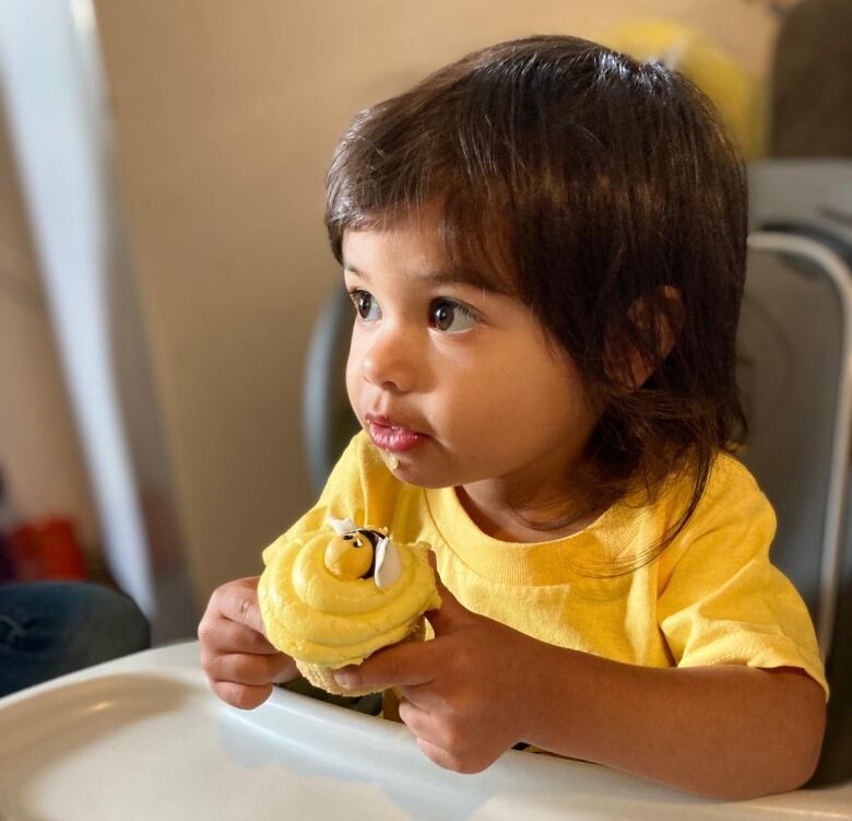 A closeup of a toddler holding a cupcake