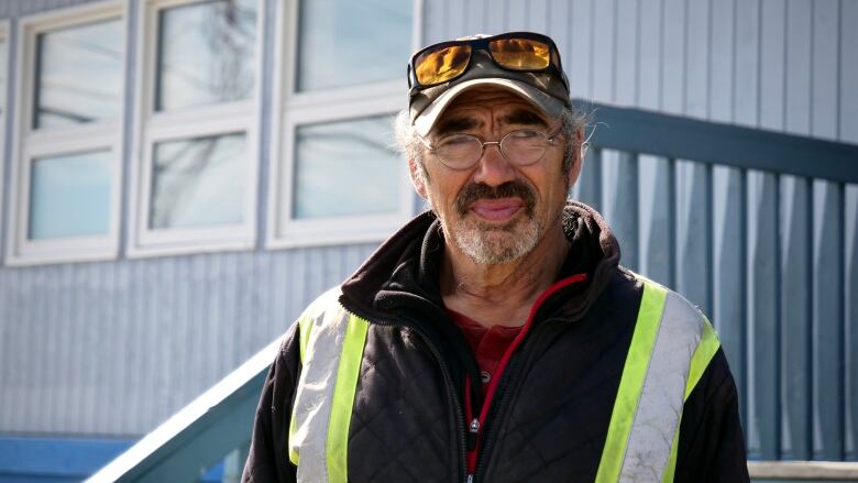 A man in a safety vest stands outside a building.