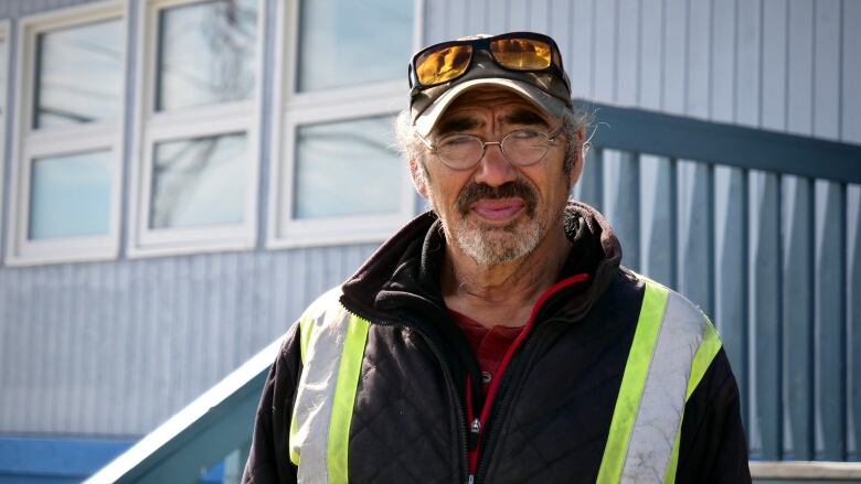 A man in a safety vest stands outside a building.