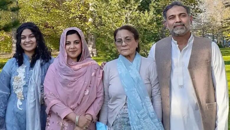 Three women wearing pastel colours and one man stand looking at the camera. 