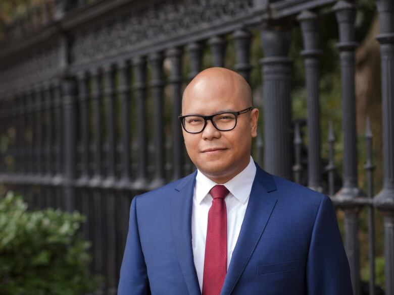 A bald Asian man in a blue suit.