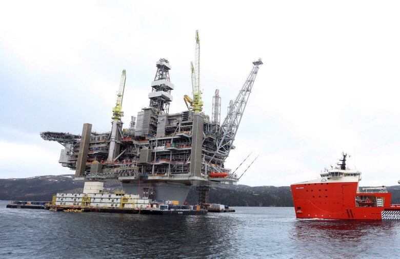 An oil rig and a large ship in the water.