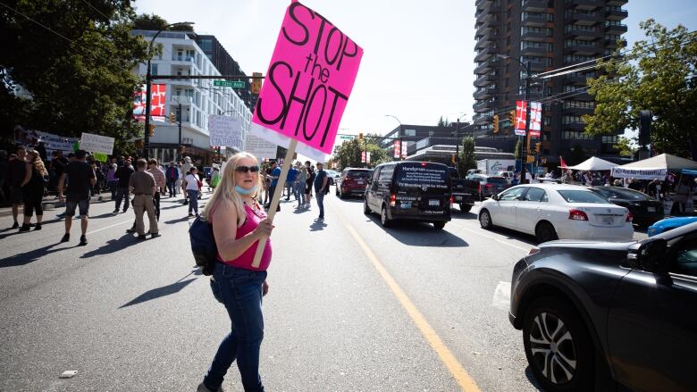 A woman in the street holds a protest sign 