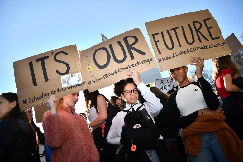 Young demonstrators hold cardboard signs that, when connected, say 