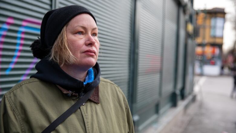 Sarah Blyth, a blonde woman wearing a toque, stands in front of a shuttered store.