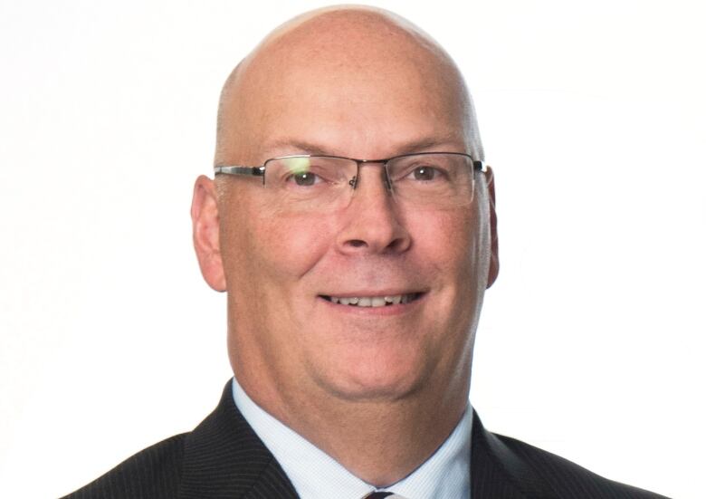 A smiling bald man in front of a white background