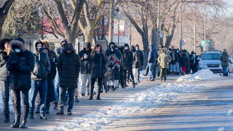 People wait in a long line in the snow.