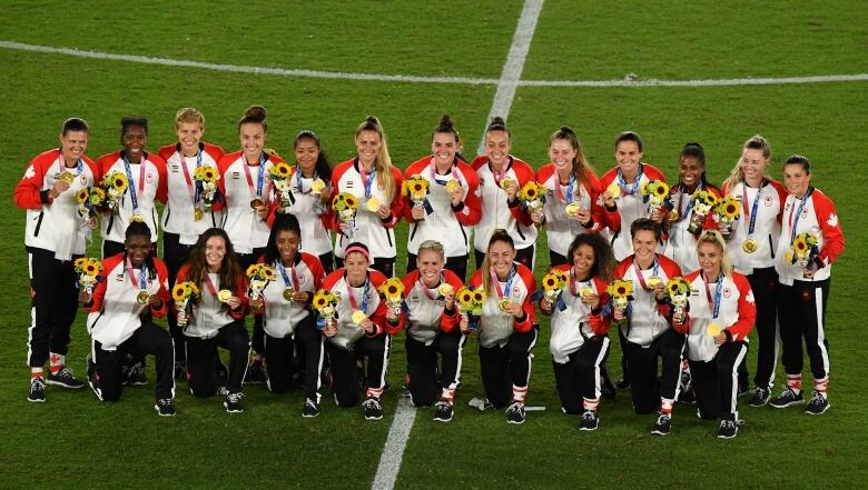 Canadian women's national team players pose in a line of two with their gold medals.