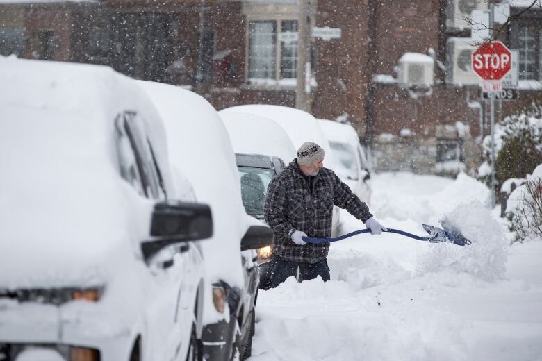 A man digs out a car in Toronto's Beaches neighbourhood after a significant dump of snow on Jan. 17, 2022.