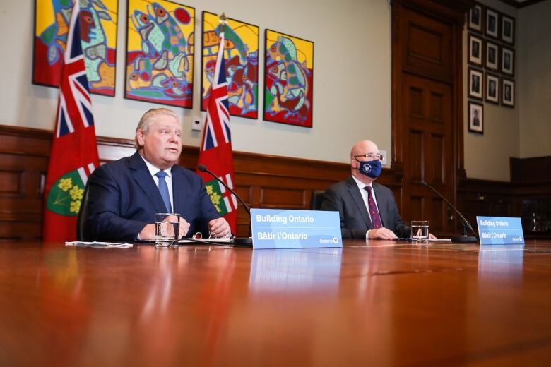 Ontario Premier Doug Ford sits with Municipal Affairs and Housing Minister Steve Clark at a boardroom table.