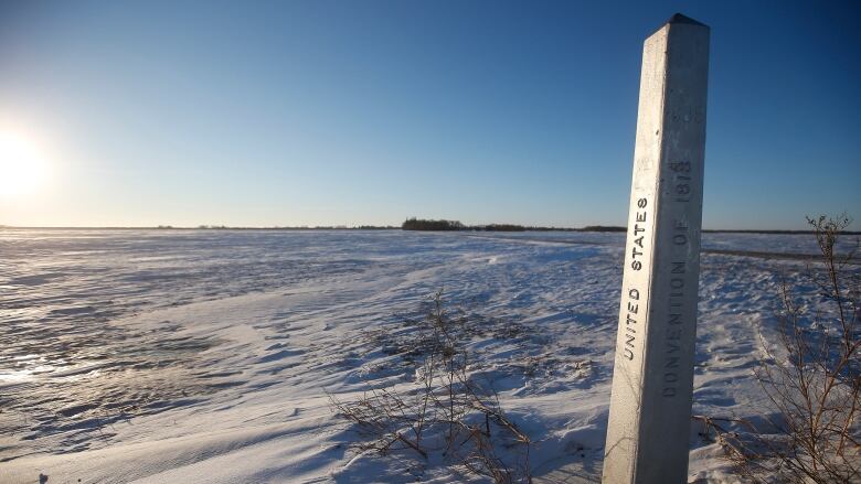 A snowy field with a concrete border marker in one corner.