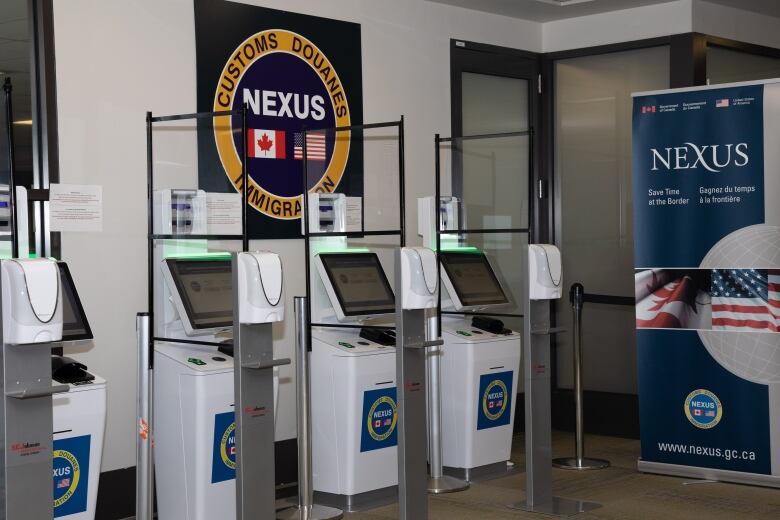 A row of immigration checking machines with the NEXUS branding on it in an airport.