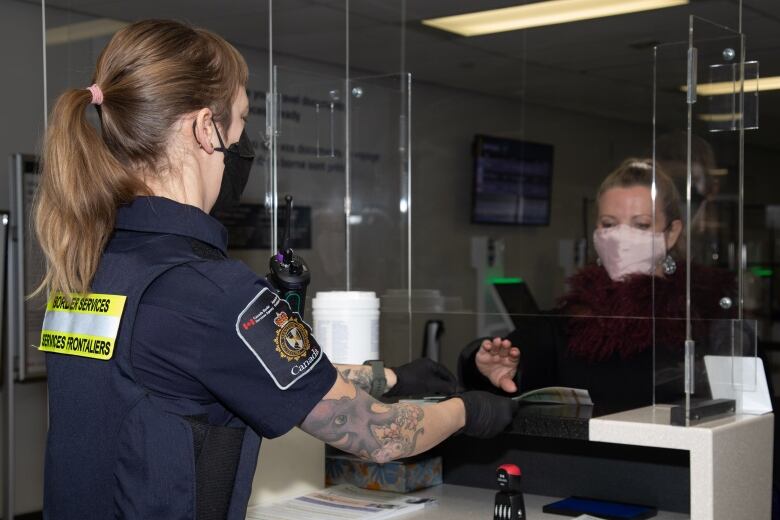 A border services agency officer takes the fingerprint of a passenger at an airport.