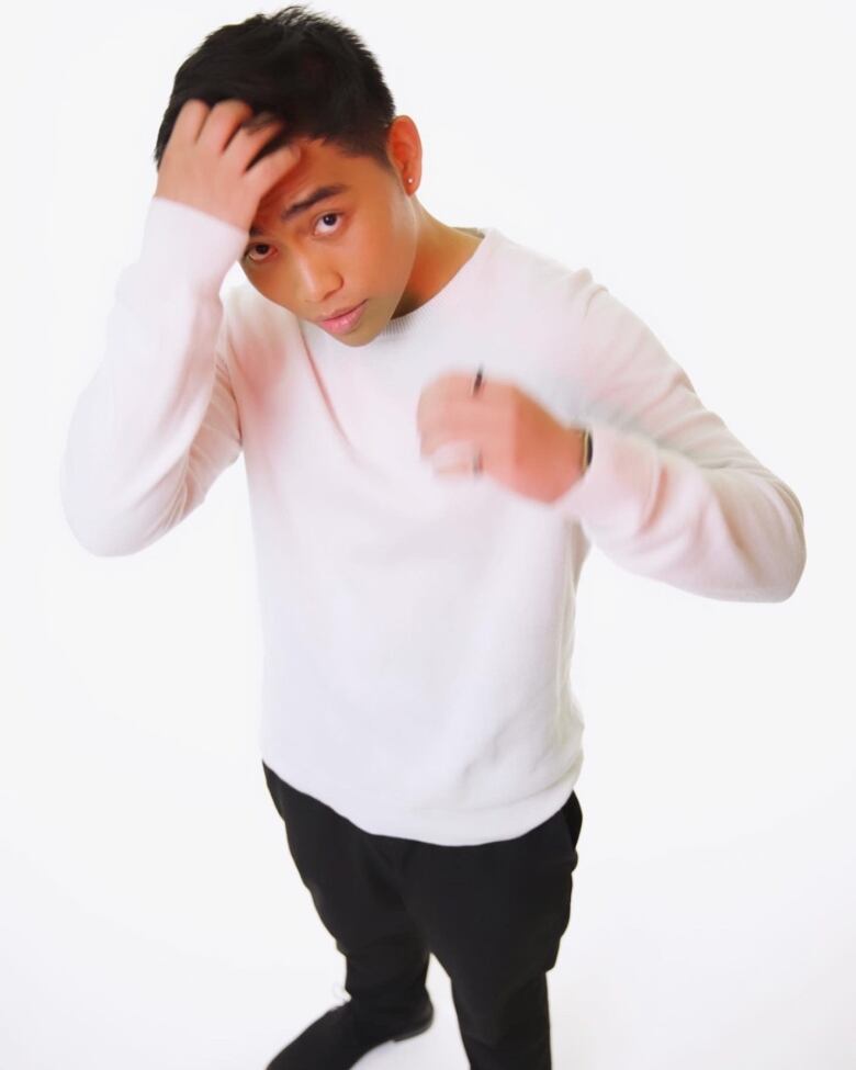 A young Filipino boy in a white long sleeve shirt and black pants adjusts his air