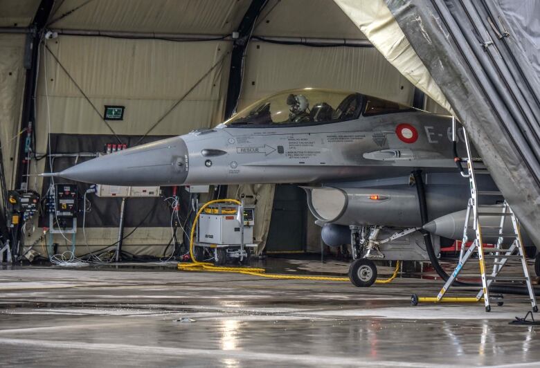 A fighter jet is parked on an airport tarmac.