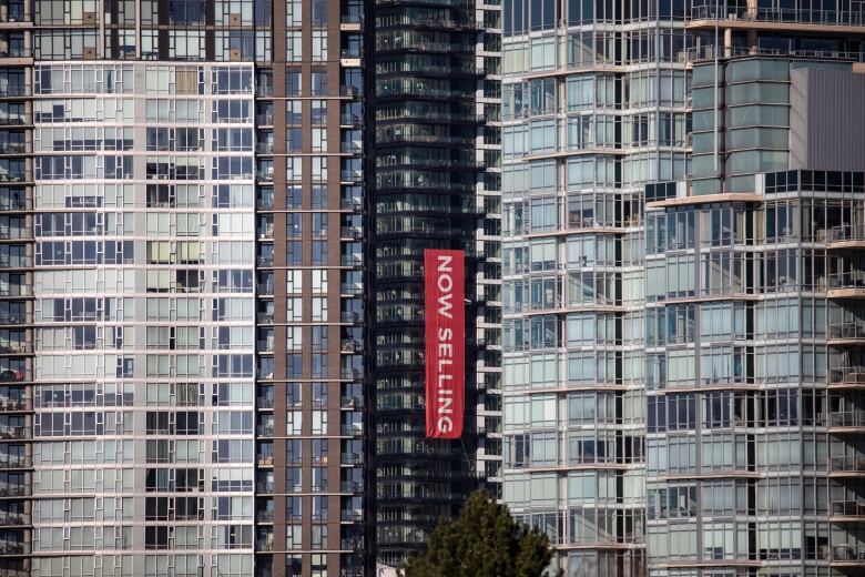 A 'now selling' banner is draped along the side of an apartment building.