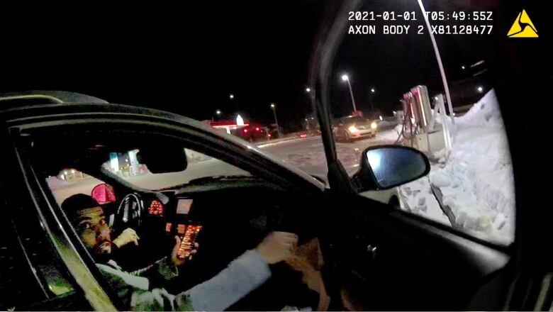 A man sits in the passenger seat of a vehicle with the door open.